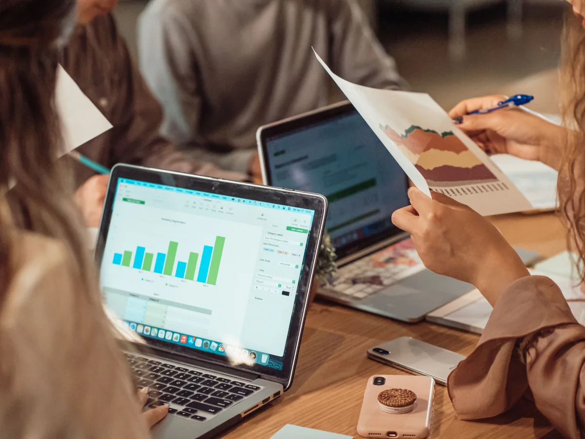 People reviewing charts and reports together at a table with laptops